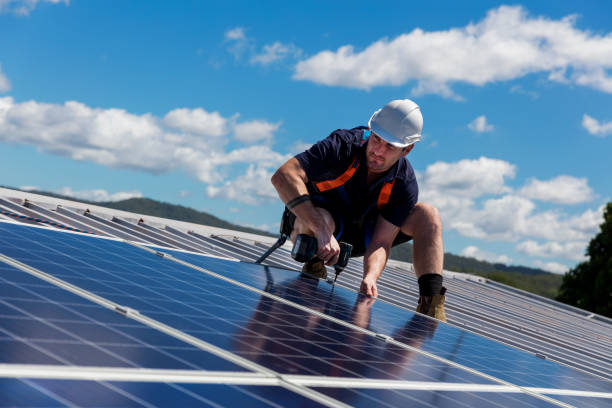 solar panel installer with drill installing solar panels on roof on a sunny day